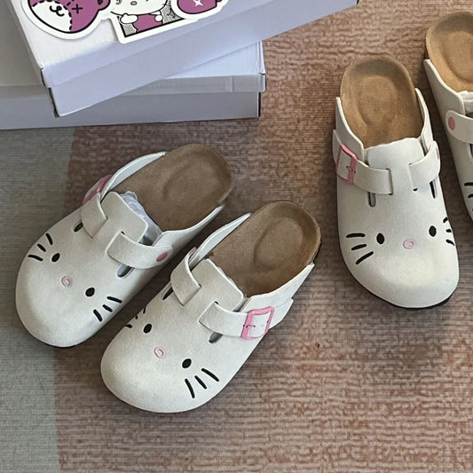 White Hello Kitty flat mule slippers with pink buckle straps and embroidered face.