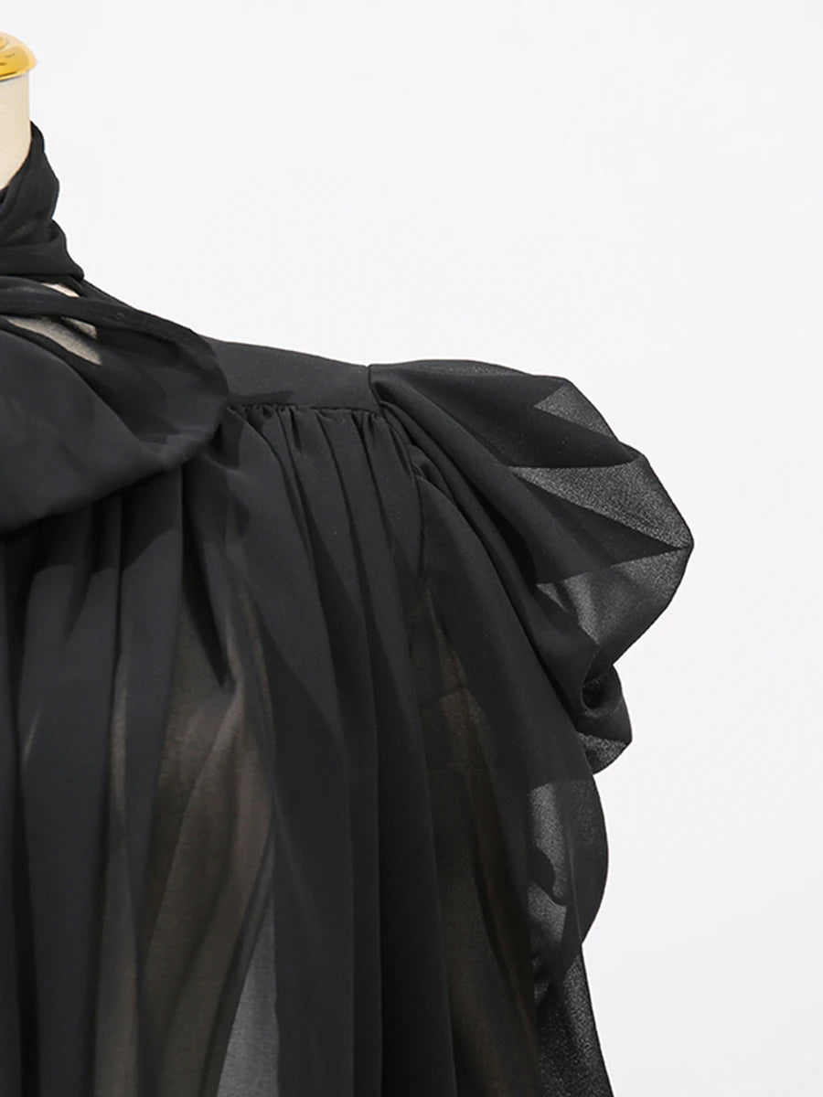 Black fabric with a draped design on a mannequin against a white background