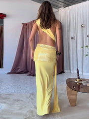 Woman wearing a yellow dress with a high slit in a room with white walls and a wooden floor.