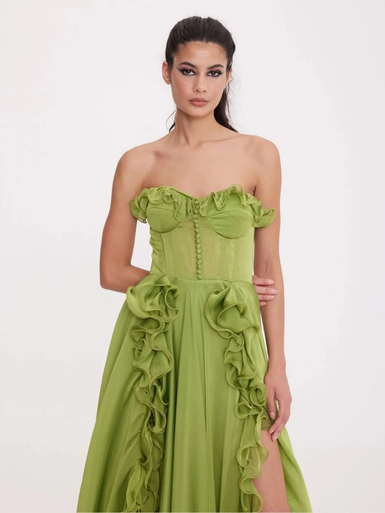 Woman wearing a strapless green dress with ruffled details on a white background