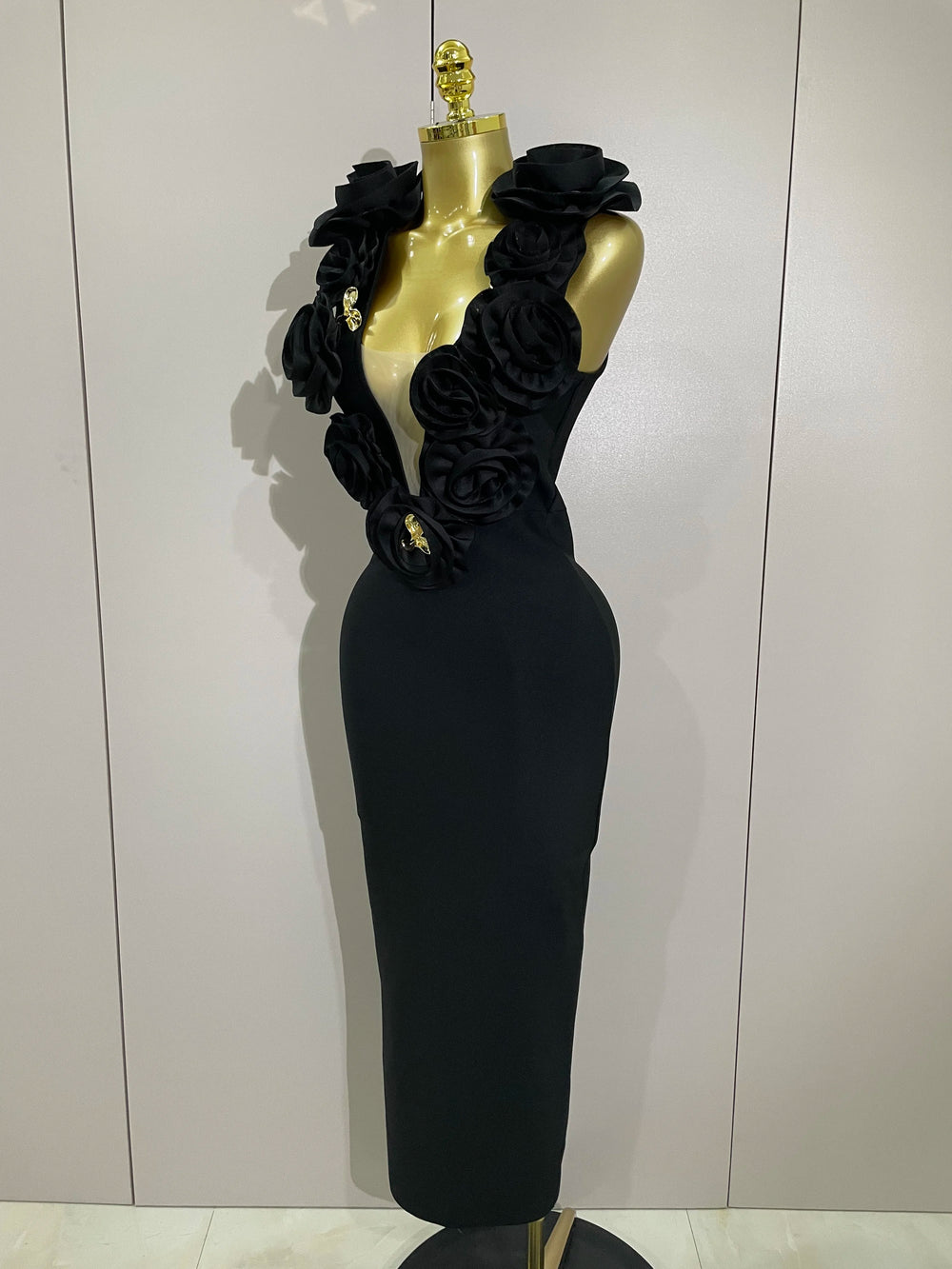Black evening gown with floral embellishments on a mannequin against a white background