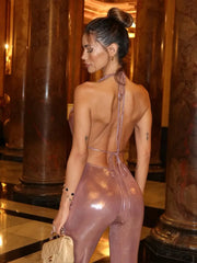 Woman in a shiny pink outfit standing in an elegant interior setting.