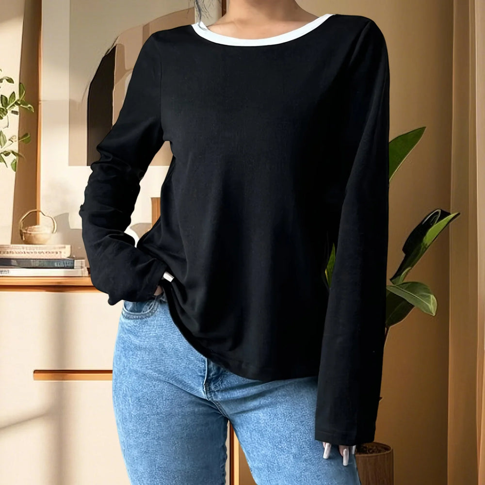 Person wearing a black long-sleeve top and blue jeans indoors.