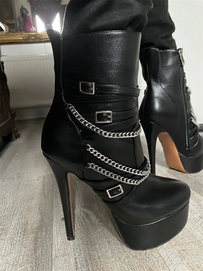 Close-up of black platform stiletto ankle boots with chain and buckle detail