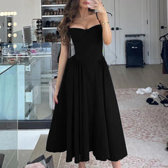 Woman wearing a black dress in a room with a desk and shelves.