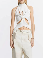 Woman wearing a white halter top with cut-out design and beige pants on a light gray background