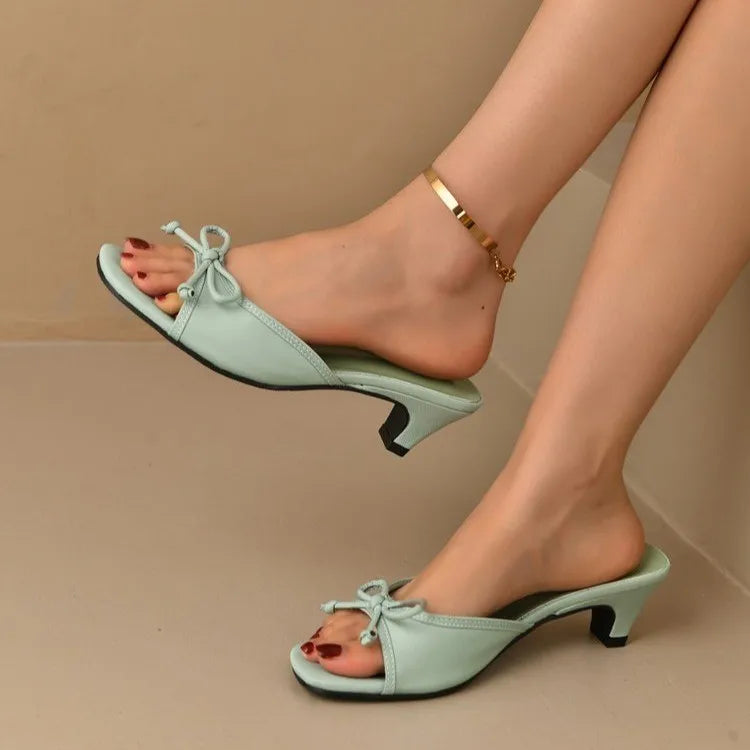 Light green high-heeled shoes worn by a person on a beige background
