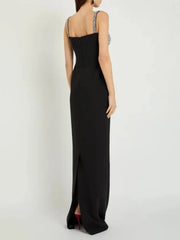 Black evening gown with thin straps and a slit on a white background