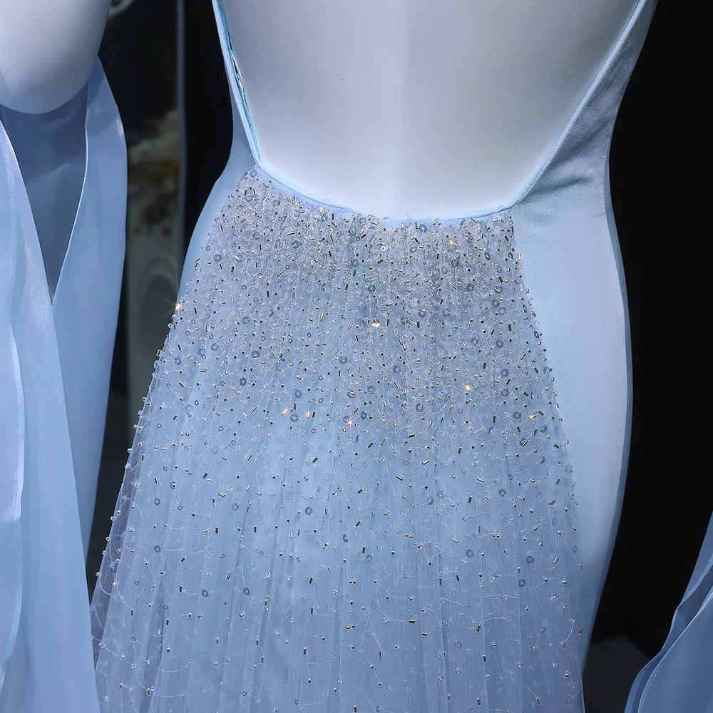 Close-up of a light blue evening gown with a beaded skirt on a black background
