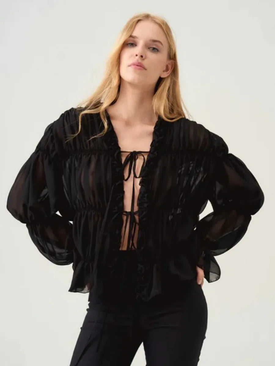 Woman wearing a black sheer blouse with long sleeves on a white background
