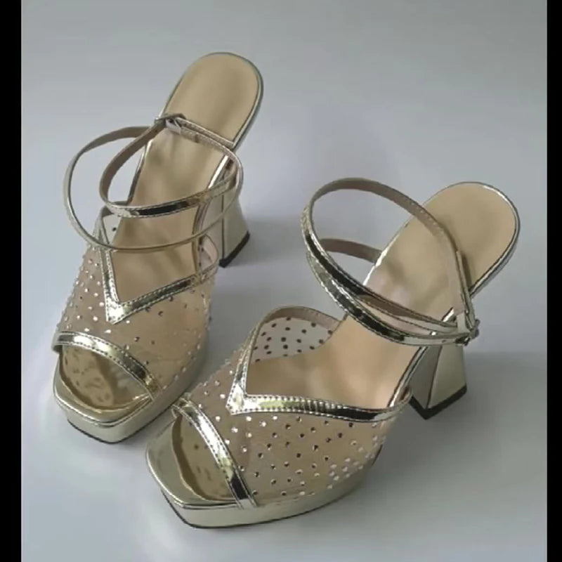 Pair of gold high-heeled sandals on a white background