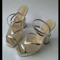 Pair of gold high-heeled sandals on a white background