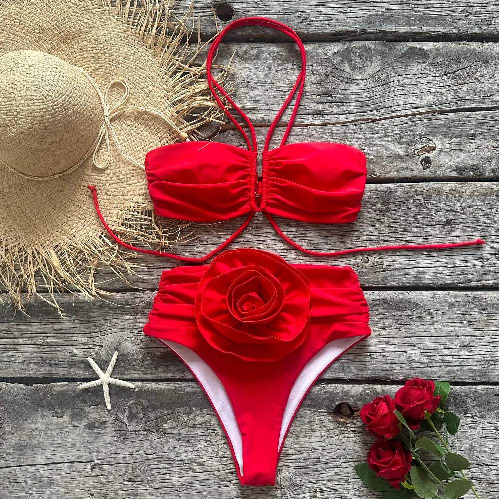 Flat lay of a red bikini set with ruched details and a rose embellishment.