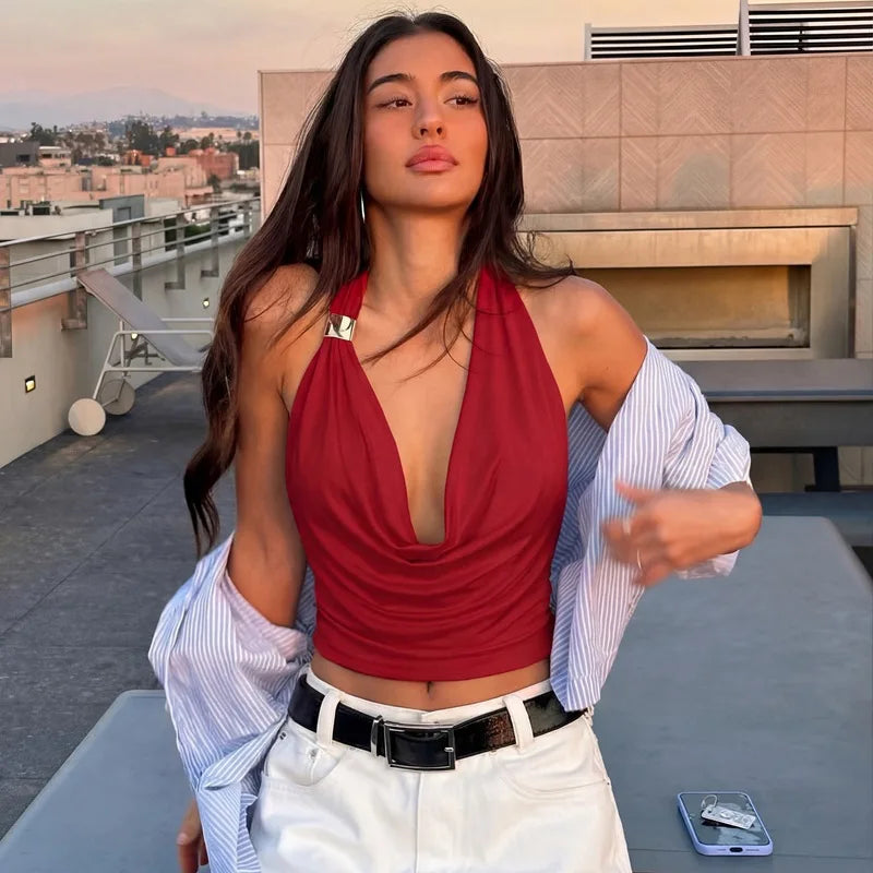 Woman in a red top and white pants on a rooftop with a cityscape background
