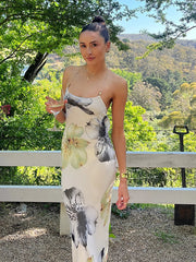 Woman in a floral dress standing outdoors with greenery in the background