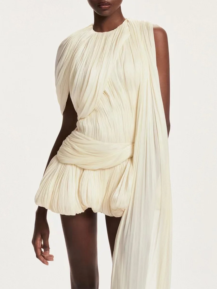 Woman wearing a flowing white dress against a plain background