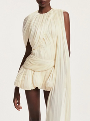 Woman wearing a flowing white dress against a plain background