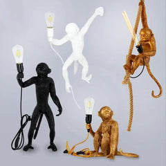 A playful retro monkey chandelier with three monkeys hanging from a branch, illuminating a modern coffee shop. Gold, White, Black