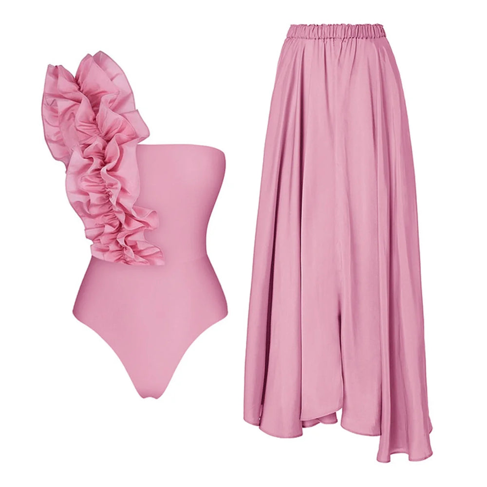 Two-piece pink swimsuit set with ruffled one-shoulder top and maxi skirt.