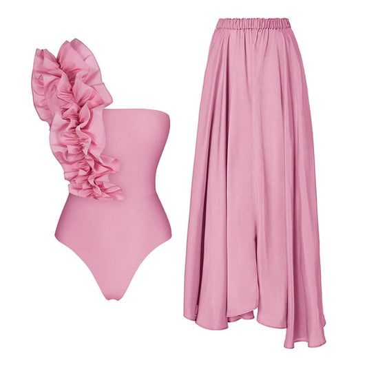 Two-piece pink swimsuit set with ruffled one-shoulder top and maxi skirt.
