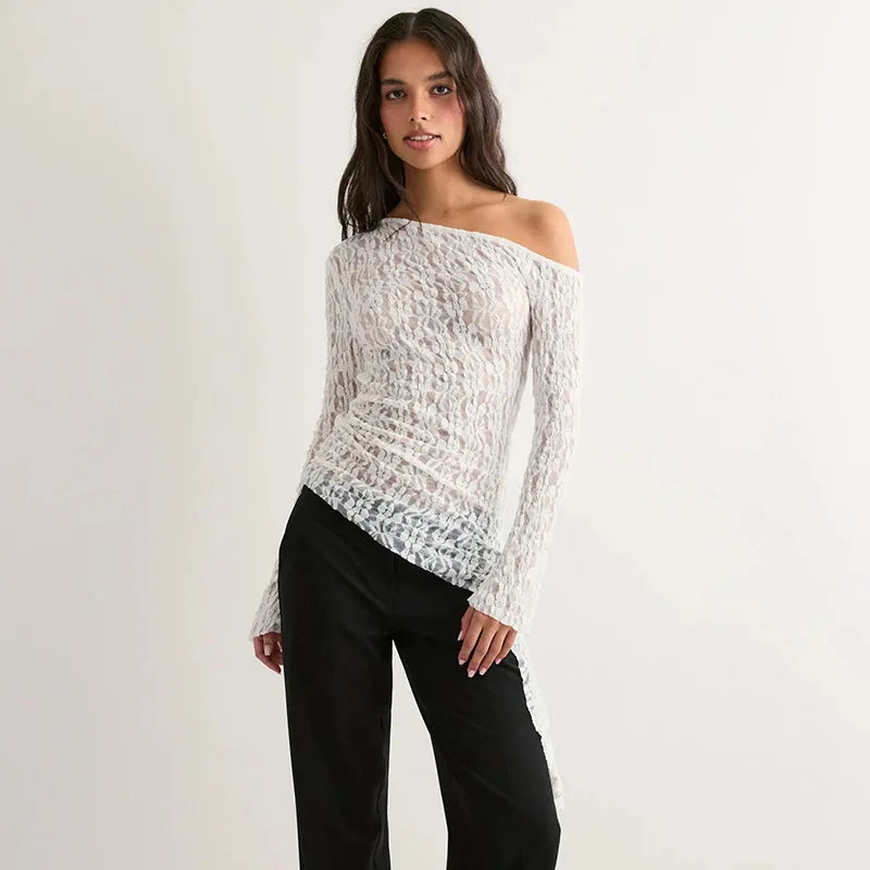 Woman wearing a white off-shoulder top and black pants against a plain background