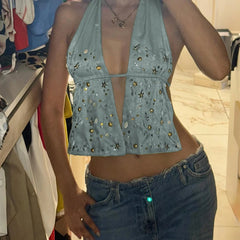 Person wearing a light blue embellished top and jeans in a casual setting.