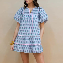 Woman wearing a light blue floral dress against a beige background