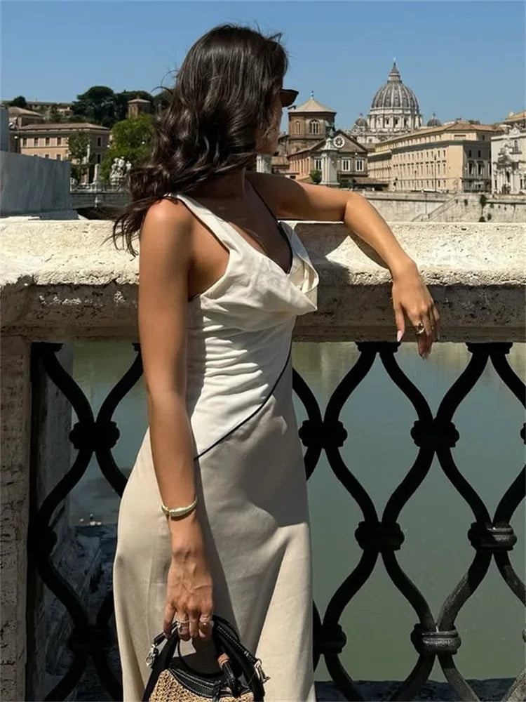 Woman in a white dress leaning on a railing with a cityscape in the background
