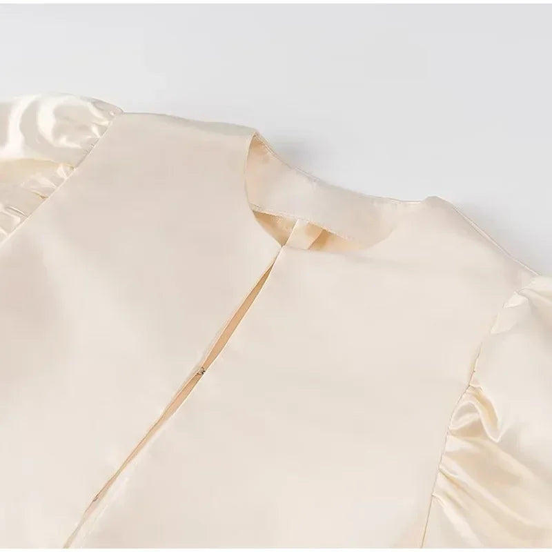 Close-up of a beige satin fabric top with a plain background