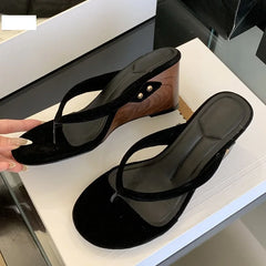 Black flock wedge heel flip flop sandals being held
