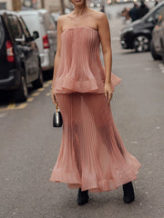 Woman in strapless top and pleated midi skirt set with handbag