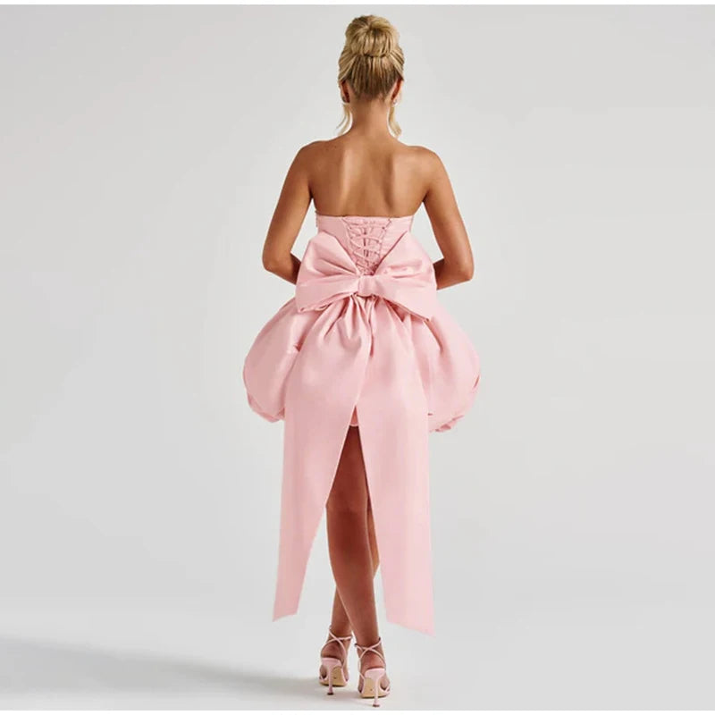 Pink strapless dress with a large bow detail on a white background