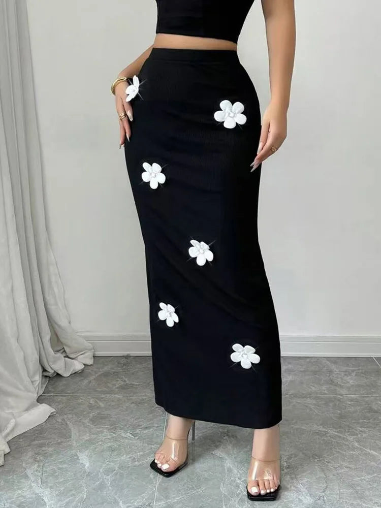 Black skirt with white floral patterns worn by a person against a neutral background