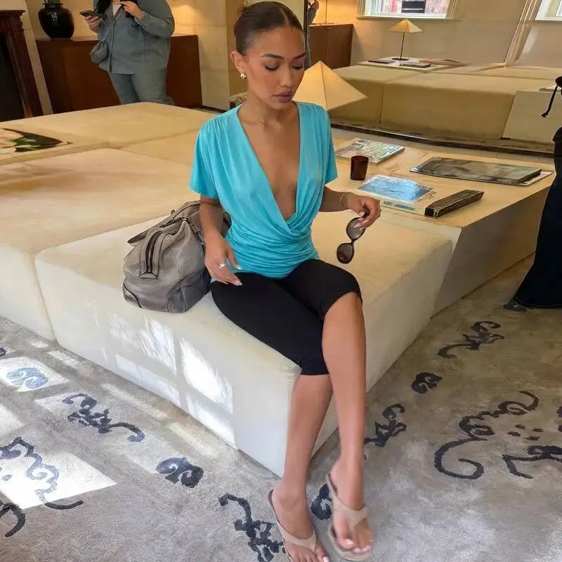 Woman wearing a blue V-neck ruched crop top while seated