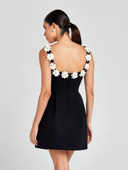 Black dress with white floral details on a plain background