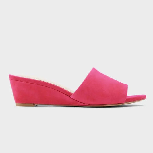 Hot pink wedge heel open toe mules on a white background
