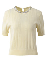 Cream-colored sweater with decorative neckline on a white background