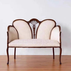 Vintage-style loveseat with wooden frame and cream upholstery on a plain background