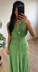 Woman wearing a green dress taking a mirror selfie indoors.