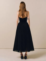 Woman wearing a black dress with thin straps on a beige background