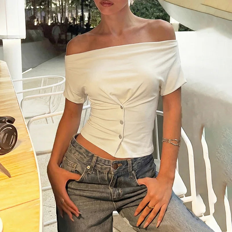 Person wearing a white off-shoulder top and blue jeans outdoors.