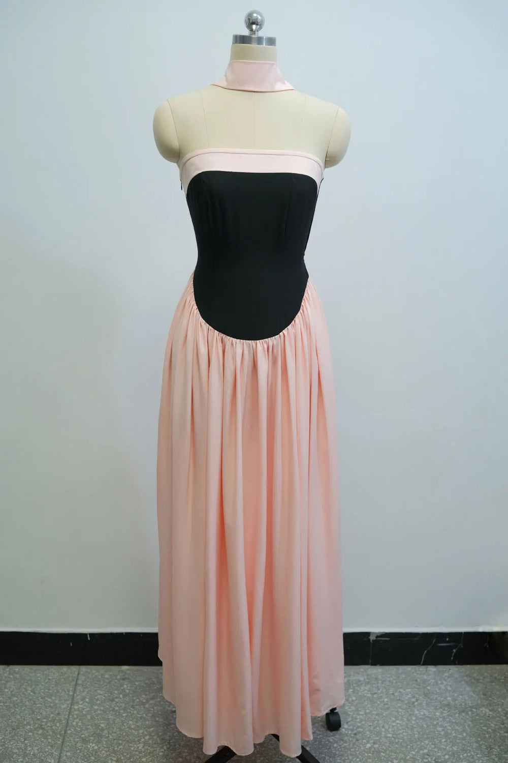 Mannequin wearing a black bodice and pink skirt against a plain background