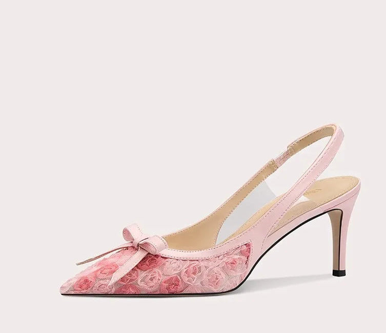 Pink high-heeled shoe with floral design and bow on a light gray background