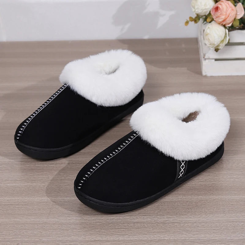 Black slippers with white fuzzy tops on a wooden floor.
