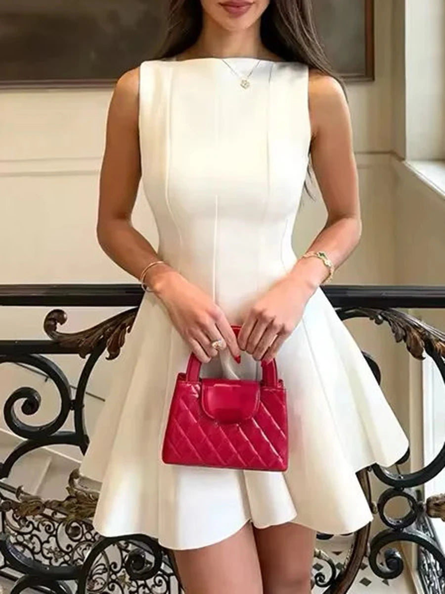 Woman in a white dress holding a pink handbag in an elegant indoor setting.