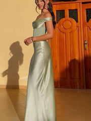 Woman in a light green strapless gown standing in front of a wooden door.