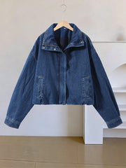 Blue denim jacket on a hanger against a neutral background