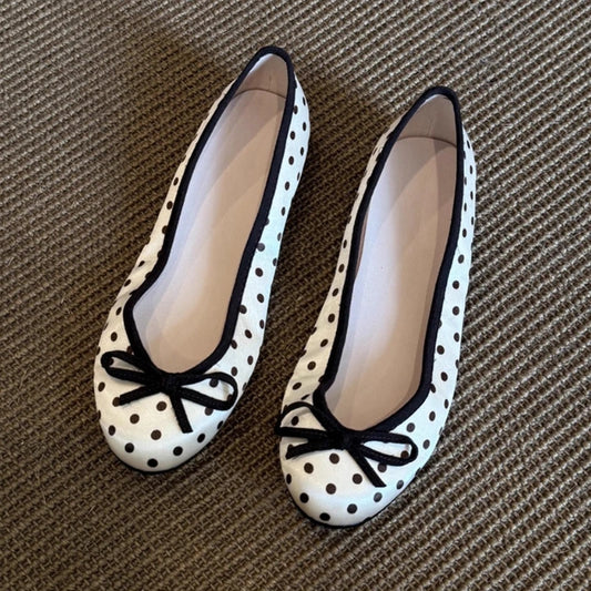 White polka dot ballet flats with black trim and a black bow