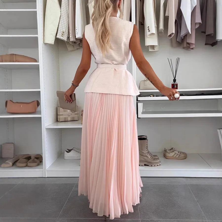 Woman in a white top and pink pleated skirt standing in a well-organized closet.