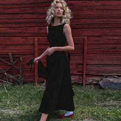 A woman wearing a  Black sleeveless A-line midi dress, showcasing the straight neckline and flared skirt. 3